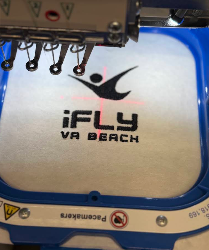 iFLY VA Beach logo being embroidered on a multi-needle machine at Ayshe Custom Embroidery Studio, Virginia Beach