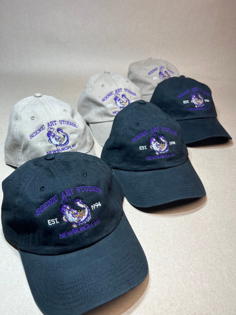 Scenic Art Studios company logo embroidered on black and khaki hats
