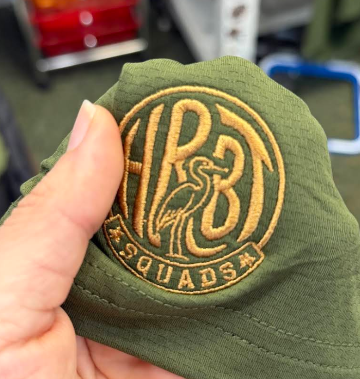 HRBT Squads logo embroidered in gold thread on an olive bucket hat